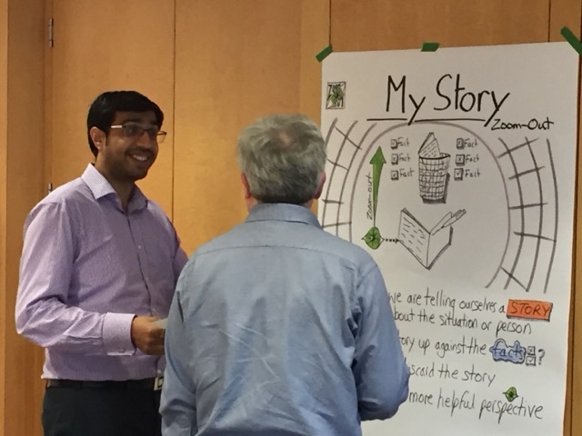 Two participants talking in front of the “My Story” Zoom-Out poster